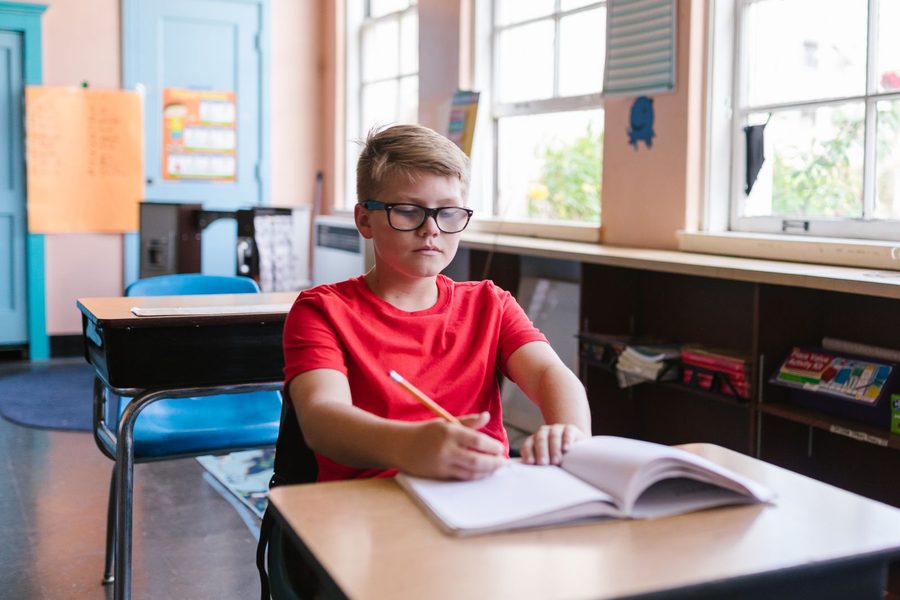 Student writing at a desk